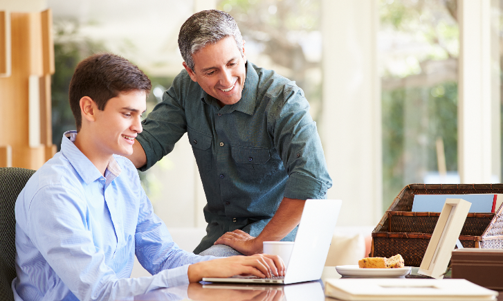 Parent helping his son on a Signpost laptop